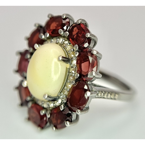 831 - An Opal, Garnet and Diamond Ring. Central 2ct opal cabochon with garnet and diamond surround. Set in... 