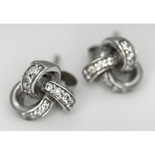 873 - A Pair of 9K White Gold Diamond Knot Stud Earrings. 1.95g.