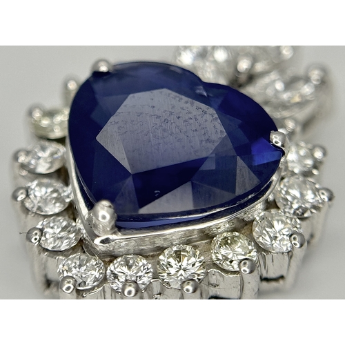 107 - An 18K White Gold, Sapphire and Diamond Pendant. A c. 2ct Madagascan heart-shaped blue sapphire with... 
