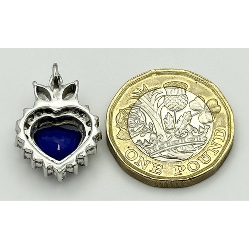 107 - An 18K White Gold, Sapphire and Diamond Pendant. A c. 2ct Madagascan heart-shaped blue sapphire with... 