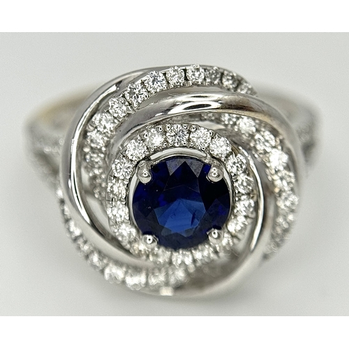72 - An 18K White Gold, Diamond and Sapphire Swirl Ring. A 0.75ct round cut sapphire is the eye in a diam... 