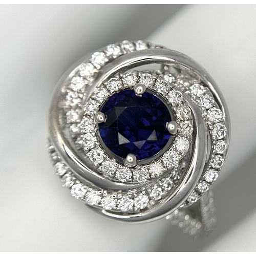 72 - An 18K White Gold, Diamond and Sapphire Swirl Ring. A 0.75ct round cut sapphire is the eye in a diam... 