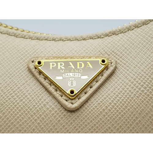 104 - A Prada Mini Re-Edition Saffiano Cream Leather Handbag. Gold-tone hardware. Comes with a certificate... 