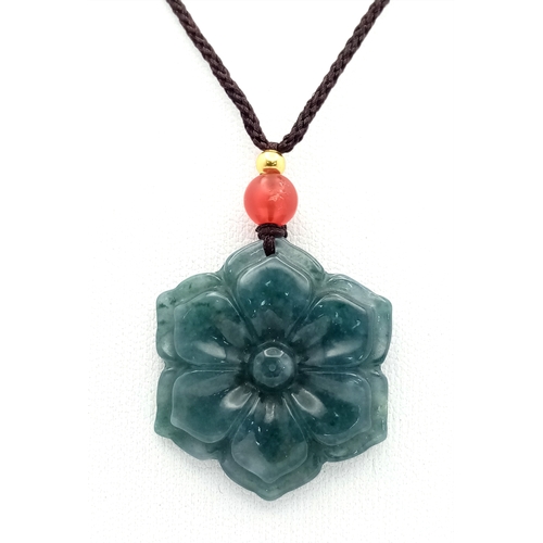 384 - A natural green jadeite blossom flower pendant on rope chain, 2.5cm diameter, 64cm rope length.