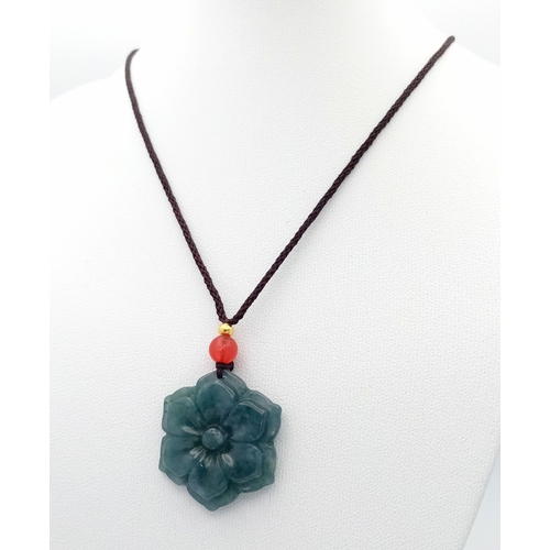 384 - A natural green jadeite blossom flower pendant on rope chain, 2.5cm diameter, 64cm rope length.