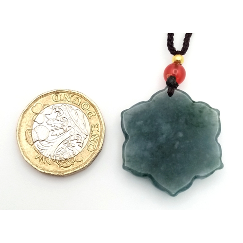 384 - A natural green jadeite blossom flower pendant on rope chain, 2.5cm diameter, 64cm rope length.