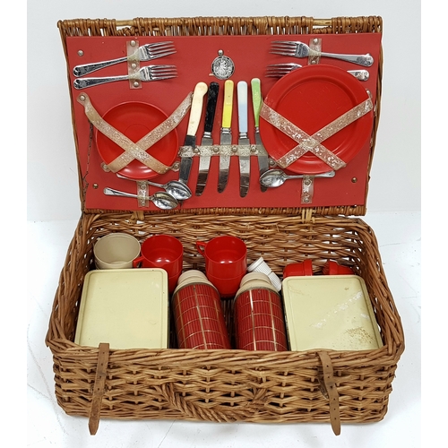 780 - A vintage wicker picnic basket with buckle fasteners, containing two original Thermos flasks, and fo... 