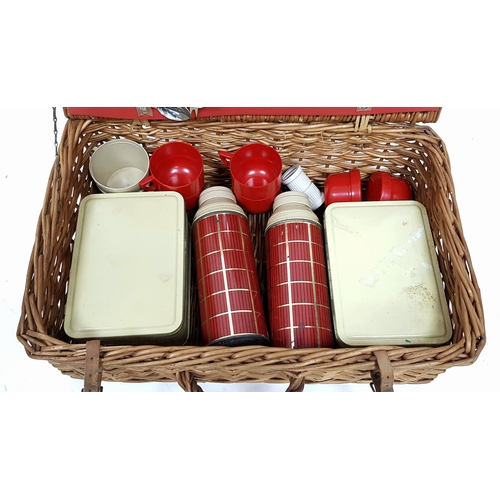 780 - A vintage wicker picnic basket with buckle fasteners, containing two original Thermos flasks, and fo... 