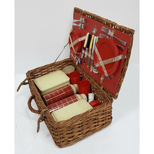 780 - A vintage wicker picnic basket with buckle fasteners, containing two original Thermos flasks, and fo... 