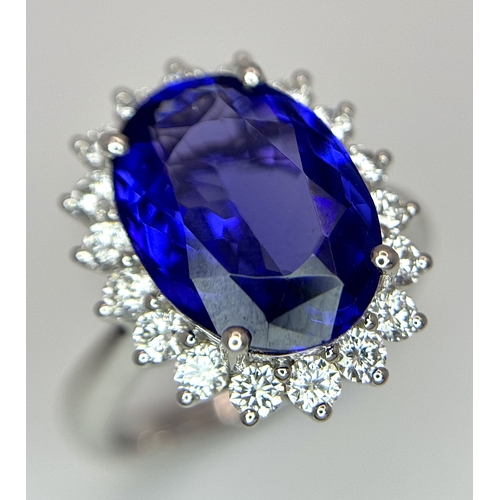 A Stunning 18K White Gold, Blue Tanzanite and Diamond Ring. A 5ct oval cut tanzanite with a round brilliant cut diamond surround - 1ctw. Absolutely stunning! Size N. 8.2g total weight. MT32.