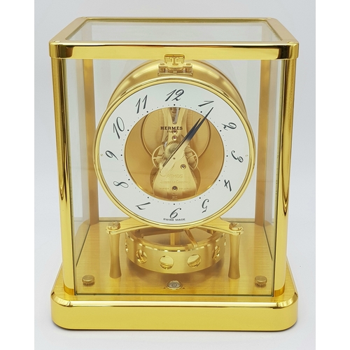 A Beautiful Jaeger-LeCoultre Hermes Gilded Mantle Clock. Atmospheric clock with white openwork dial revealing clock movement. Golden hands blackened on tips. Arabic dial. The atmospheric clock works by temperature variations that take place daily - a gas inside a flexible membrane expands when the temperature rises and compresses a spring that animates the pendulum. 20 x 23cm. In good condition.  STK025049