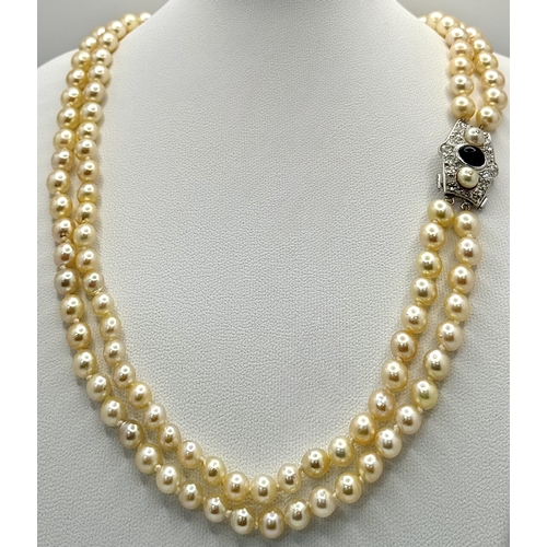 33 - A DOUBLE ROW PEARL NECKLACE WITH A PLATINUM CLASP SET WITH DIAMONDS, PEARLS AND CABACHON SAPPHIRE . ... 