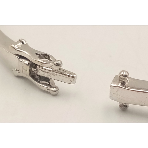 1388 - A 9K WHITE GOLD DIAMOND SET HINGED BANGLE WITH 2 SAFETY CATCHES .     7.7gms