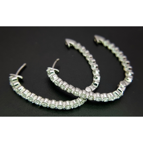1009 - A Pair of 18K White Gold and Diamond Elongated Hoop Earrings. 2.2ctw of round brilliant cut diamonds... 