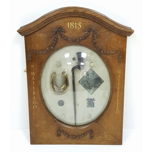 Framed Relics From The Battle of Waterloo 1815. Once displayed at the Royal Artillery Museum (Woolwich, London). Includes: Bayonet, British Officers Gorget, French Shako Plate, English Coin, French Lancers Badge and Four Lead Musket Balls. All displayed in a fine wooden, glass domed Victorian frame. 45cm x 68cm.