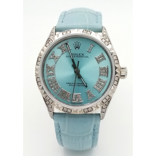 A LADIES ROLEX OYSTER PERPETUAL WATCH WITH TIFFANY BLUE DIAL AND MATCHING LEATHER STAP WITH AFTER DIAMOND ADDITION TO BEZEL AND NUMERALS. 34MM CASE. COMES WITH BOX. AS NEW CONDITION.
