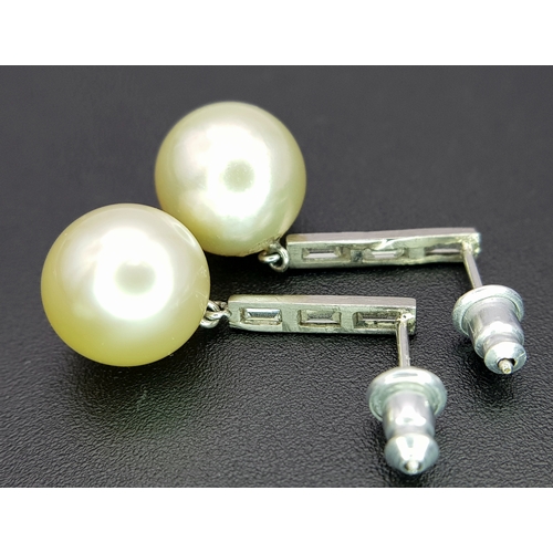1063 - A Pair of 18K White Gold (tests as) Diamond and South Sea Pearl Drop Earrings. 11mm pearls. Baguette... 