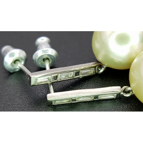 1063 - A Pair of 18K White Gold (tests as) Diamond and South Sea Pearl Drop Earrings. 11mm pearls. Baguette... 