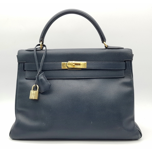 A Hermès Midnight Blue Leather Kelly Top Handle Bag. Midnight Blue leather exterior with gold-toned hardware, single rolled top handle, front flap and signature turn-lock closure, detachable shoulder strap, complete with padlock and clochette. Midnight Blue leather interior with a main compartment, two slip pockets and a zipped side pocket. Signs of wear present, including surface marks, stains and creasing to the leather. Approx 30cm length x 21cm height x 12cm depth. Comes with a dust cover. Please see photos or request a condition report.  STK024558