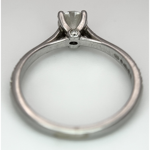 12 - A 950 Platinum and Diamond Ring. A 0.45ct round brilliant cut diamond with diamond accents on should... 