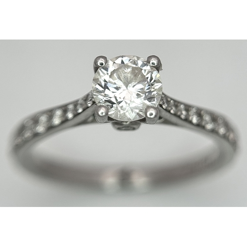 12 - A 950 Platinum and Diamond Ring. A 0.45ct round brilliant cut diamond with diamond accents on should... 