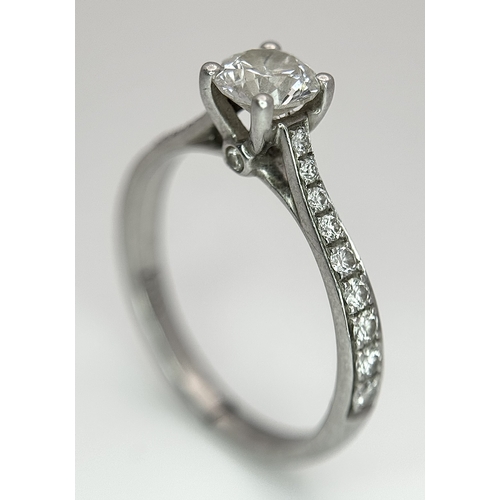12 - A 950 Platinum and Diamond Ring. A 0.45ct round brilliant cut diamond with diamond accents on should... 