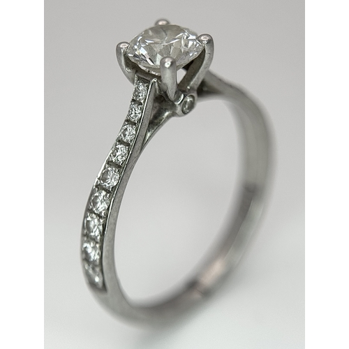 12 - A 950 Platinum and Diamond Ring. A 0.45ct round brilliant cut diamond with diamond accents on should... 