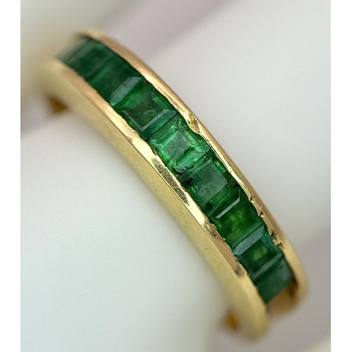 548 - An 18K Yellow Gold Channel Set Emerald Ring. Size O. Nine square shaped emeralds. 5.8g. N10/24756.