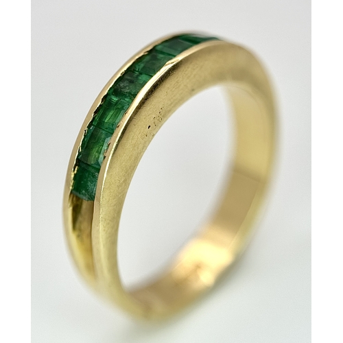 548 - An 18K Yellow Gold Channel Set Emerald Ring. Size O. Nine square shaped emeralds. 5.8g. N10/24756.