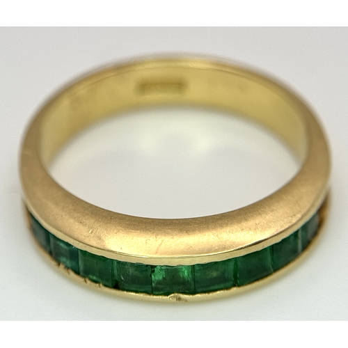 548 - An 18K Yellow Gold Channel Set Emerald Ring. Size O. Nine square shaped emeralds. 5.8g. N10/24756.
