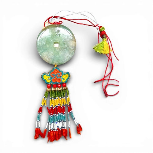 A rare example Jadeite of Indochine colonial era, an offering from the Annam people, made of light green jade with veins, perforated in the center and engraved with traditional mantras: "May you live as long as the Southern Mountains" and "May flowers bloom with blessings as abundant as the Eastern Sea." It has a hanging cord and tassels made of glass beads.
52 mm, weight: 31 g. In very good condition.