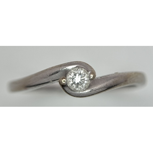 106 - An 18K White Gold Diamond Crossover Solitaire Ring. Size M. Brilliant round cut diamond c. 0.10ct. 1... 