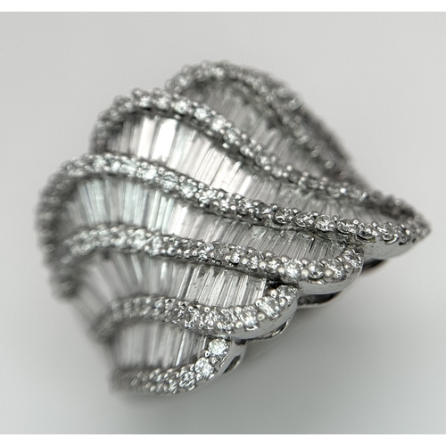 134 - An 18K White Gold and Diamond Ladies Cocktail Ring. Waves of round brilliant and baguette cut diamon... 