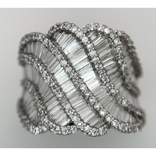 134 - An 18K White Gold and Diamond Ladies Cocktail Ring. Waves of round brilliant and baguette cut diamon... 