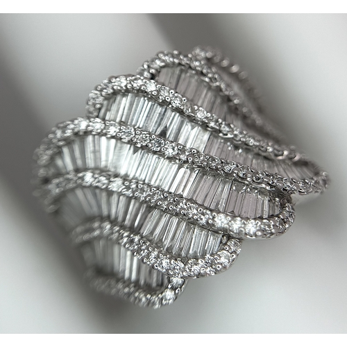 134 - An 18K White Gold and Diamond Ladies Cocktail Ring. Waves of round brilliant and baguette cut diamon... 