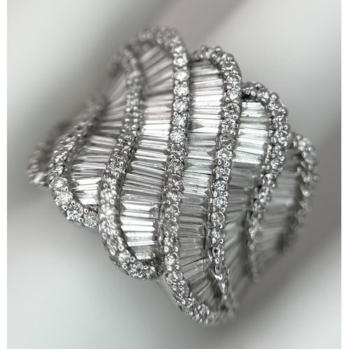 134 - An 18K White Gold and Diamond Ladies Cocktail Ring. Waves of round brilliant and baguette cut diamon... 