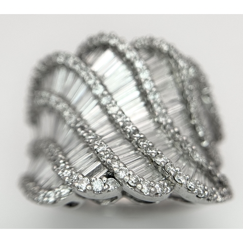 134 - An 18K White Gold and Diamond Ladies Cocktail Ring. Waves of round brilliant and baguette cut diamon... 