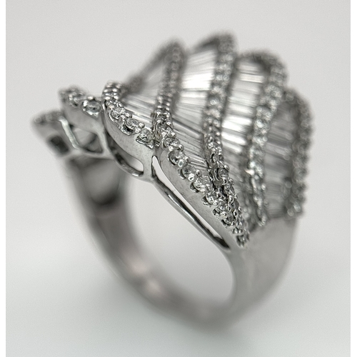 134 - An 18K White Gold and Diamond Ladies Cocktail Ring. Waves of round brilliant and baguette cut diamon... 
