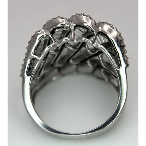 134 - An 18K White Gold and Diamond Ladies Cocktail Ring. Waves of round brilliant and baguette cut diamon... 