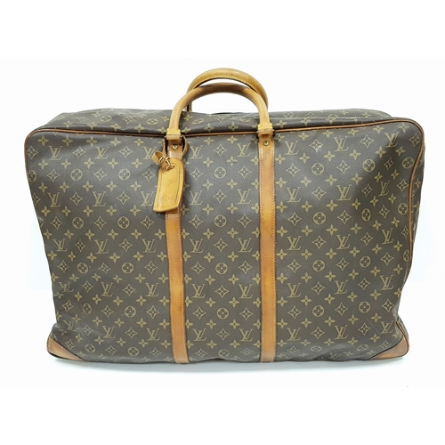 A Louis Vuitton Brown Monogram Keepall Travel Bag. Brown monogram coated canvas exterior with gold-toned hardware, double rolled leather handles, a leather tag and zipped top closure. Beige textile interior with a single main compartment, an opened section with snap button and adjustable interior straps. Some signs of wear, stains and scratches to the exterior and interior. Approx 63cm length x 42cm height x 21cm width. Please see photos or request a condition report. Ref: 26984.