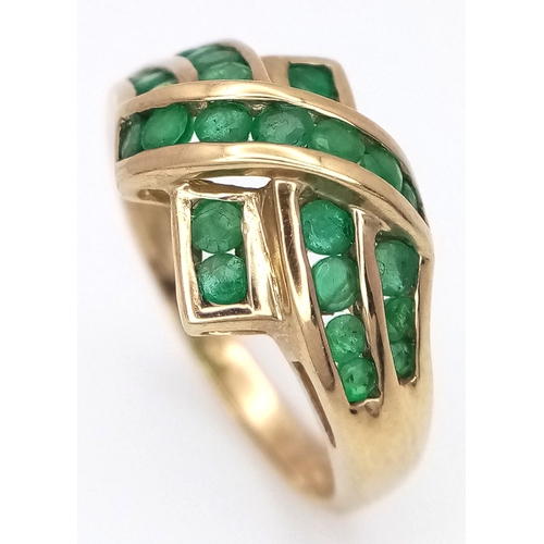 1032 - A 9K Yellow Gold Emerald Crossover Ring. Channel set stones. Size O. 3g total weight.