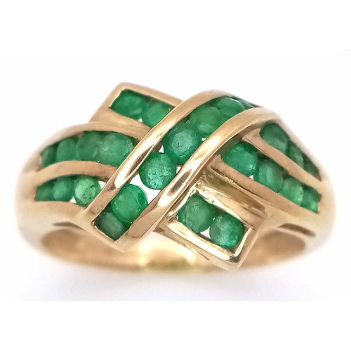 1032 - A 9K Yellow Gold Emerald Crossover Ring. Channel set stones. Size O. 3g total weight.