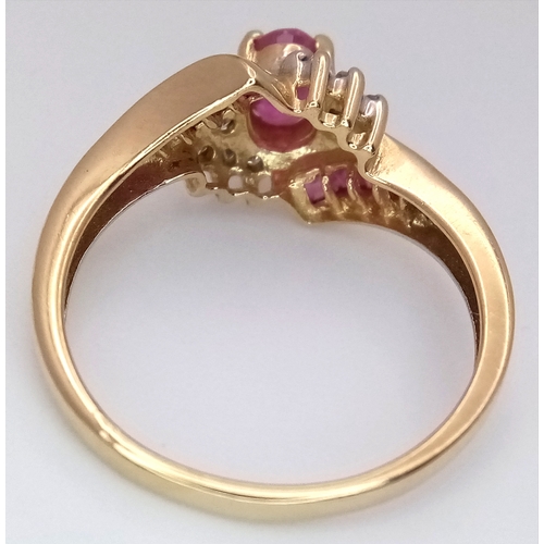 1039 - A 9K Yellow Gold Ruby and Diamond Crossover Ring. Oval and square cut rubies with small diamond acce... 