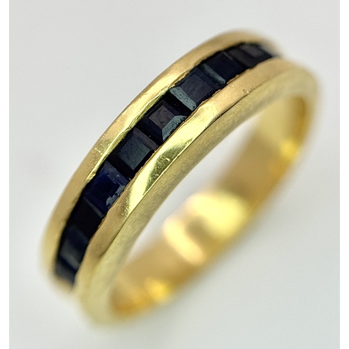 1117 - An 18K Yellow Gold Sapphire Channel Set Ring. 10 square cut sapphires. Size N. 5.4g. NL-2440.