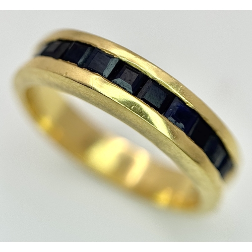 1117 - An 18K Yellow Gold Sapphire Channel Set Ring. 10 square cut sapphires. Size N. 5.4g. NL-2440.