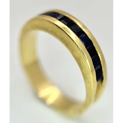 1117 - An 18K Yellow Gold Sapphire Channel Set Ring. 10 square cut sapphires. Size N. 5.4g. NL-2440.