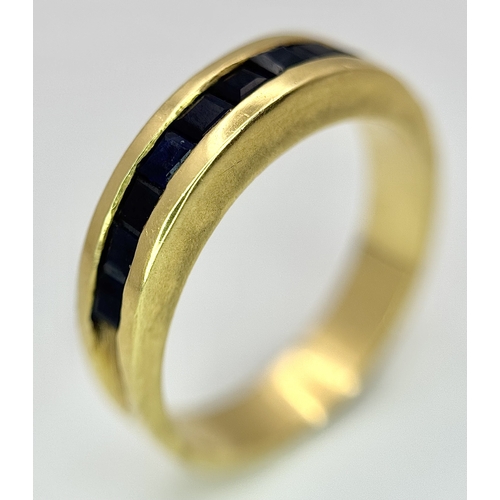 1117 - An 18K Yellow Gold Sapphire Channel Set Ring. 10 square cut sapphires. Size N. 5.4g. NL-2440.