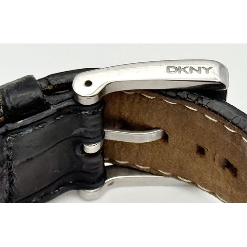 1064 - A DKNY, STONE SET, SQUARE FACE, BLACK LEATHER STRAP WATCH. WITH ORIGINAL STRAP AND BUCKLE. IN FULL W... 