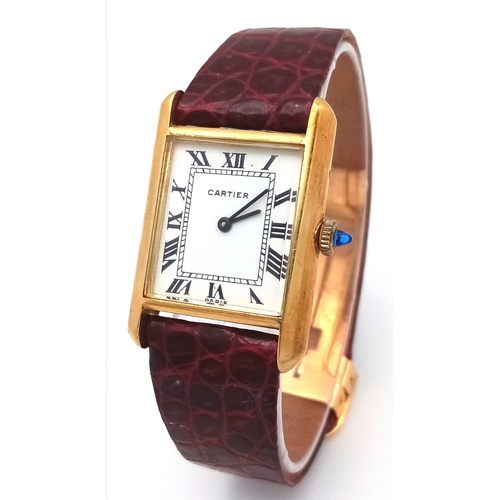 A Vintage Cartier Mechanical (hand-wind) Gold Tank Ladies Watch. Red leather strap with 18K gold Cartier clasp. 18k gold tank case - 25mm x 34mm. White dial with Roman numerals. In working order. R26391.