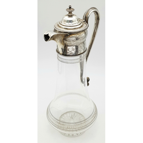 141 - An Antique Victorian Cut Glass Claret Jug with Sterling Silver Scrolled Handle, Lid with ornate fini... 